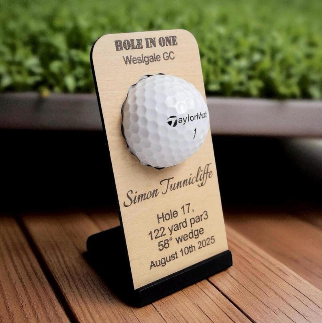 Personalised wooden hole-in-one golf ball display plaque featuring a golf course background, club name, and player details.